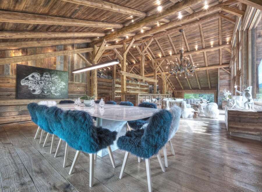 Experience luxury living in this stunning property featuring a spacious dining area with a modern marble table and stylish blue fur chairs.