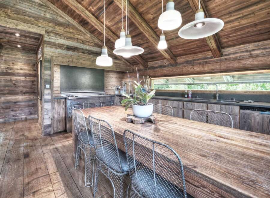 Experience rustic elegance in this stunning kitchen! Featuring a large wooden dining table, wire chairs, and a cozy wooden ceiling, this space is perfect for gatherings.
