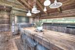 Experience rustic elegance in this stunning kitchen! Featuring a large wooden dining table, wire chairs, and a cozy wooden ceiling, this space is perfect for gatherings.