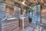 Experience luxury in this stunning bathroom featuring a rustic wooden vanity and sleek stone accents.