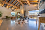 Experience luxury living in this stunning property featuring a modern fireplace, exposed wooden beams, and expansive windows offering breathtaking mountain views.