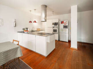 This modern kitchen boasts sleek white cabinetry and a spacious island, perfect for culinary enthusiasts.