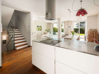 Experience modern living in this stunning property, featuring a sleek kitchen island with a built-in cooktop and ample storage.