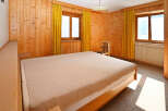 This cozy bedroom features warm wooden paneling and a comfortable bed, creating a welcoming atmosphere.