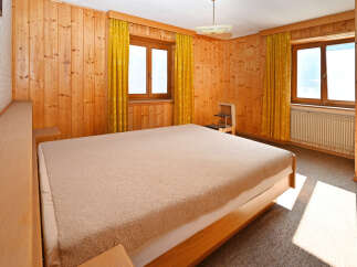 This cozy bedroom features warm wooden paneling and a comfortable bed, creating a welcoming atmosphere.