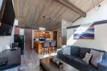 This stunning property boasts a cozy living space with a rustic charm, featuring a beautiful wooden ceiling and a stone accent wall.