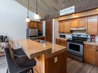 This stunning kitchen boasts a modern design with beautiful wooden cabinetry and a spacious granite countertop island, perfect for entertaining.