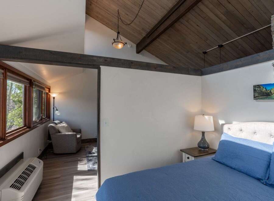 Discover the charm of this inviting bedroom, featuring a cozy seating area and a comfortable bed.
