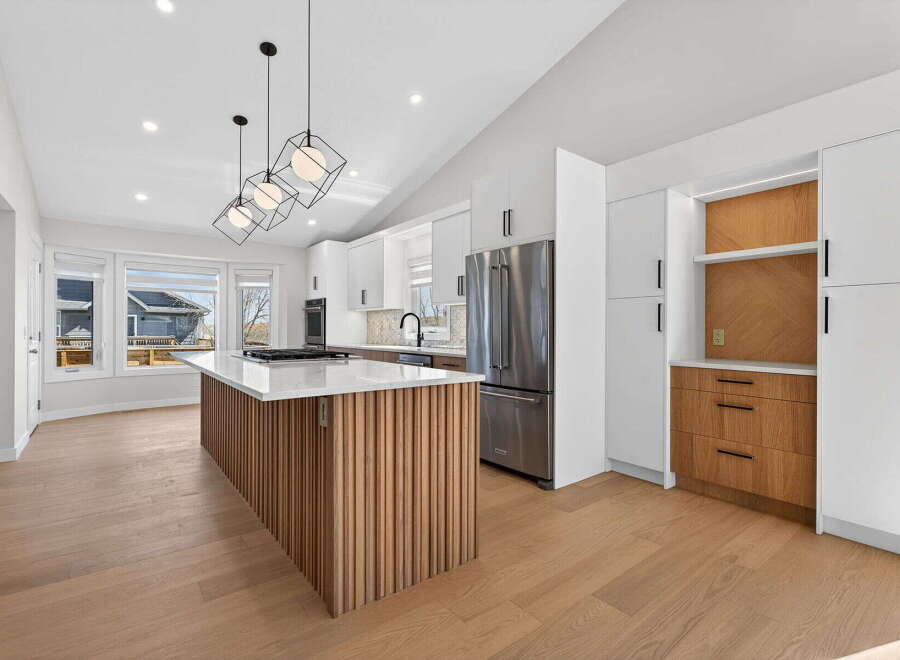 This stunning kitchen boasts a modern design with sleek white cabinetry and a striking wooden island.
