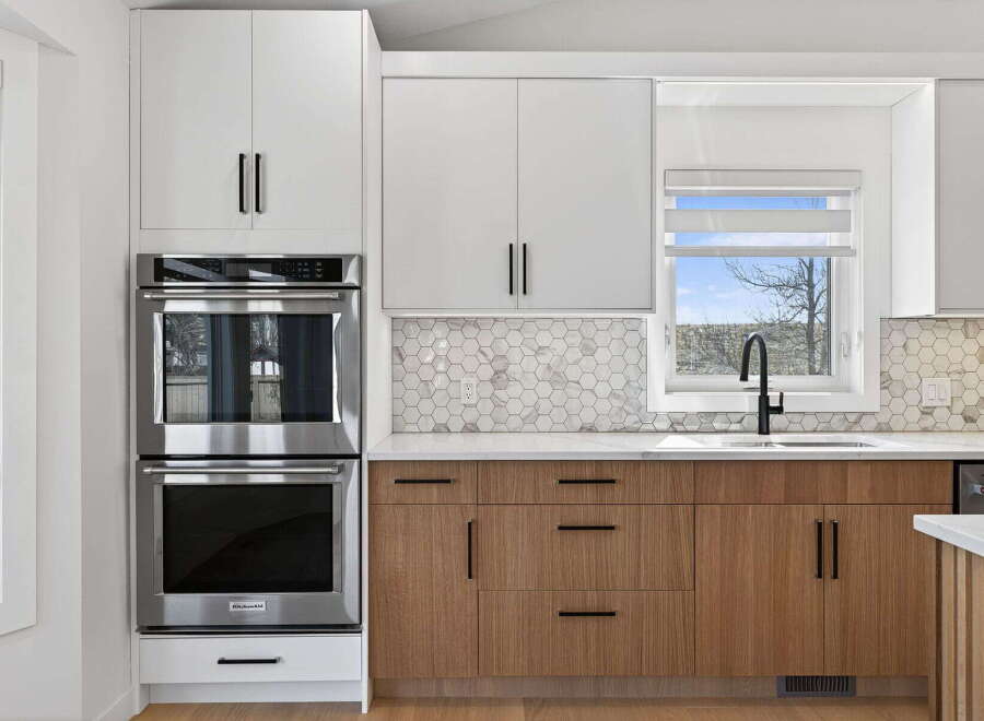 This modern kitchen boasts sleek, white cabinetry paired with warm wood accents, creating a harmonious blend of style and functionality.