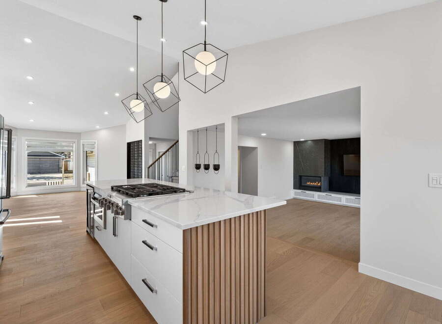 This stunning kitchen boasts modern design with sleek white cabinetry, a marble countertop, and a stylish island.