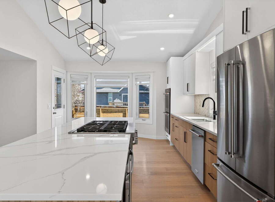 This stunning kitchen boasts modern design with sleek white cabinetry and a spacious island with a cooktop.