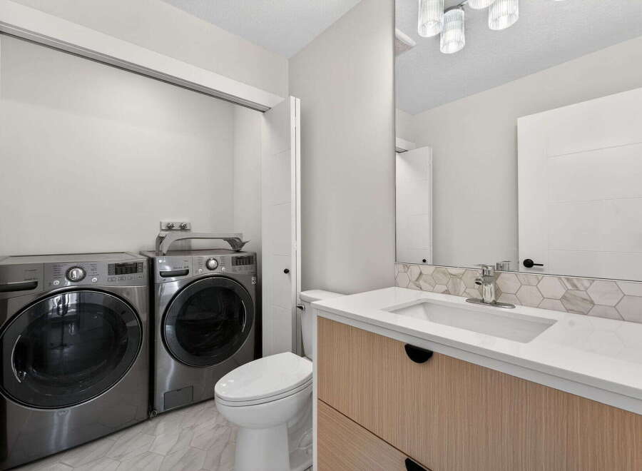 Discover modern living in this stunning property! Featuring a convenient laundry area with a washer and dryer, and a stylish bathroom with a sleek vanity and sink.