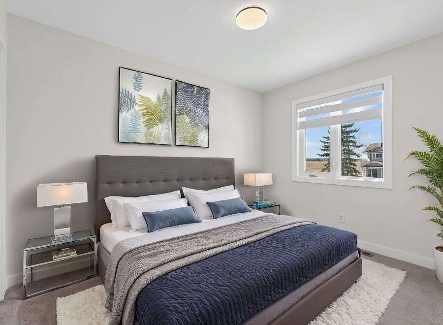 Step into this beautifully designed bedroom, featuring a cozy bed adorned with plush pillows and a stylish navy blue quilt.