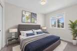 Step into this beautifully designed bedroom, featuring a cozy bed adorned with plush pillows and a stylish navy blue quilt.