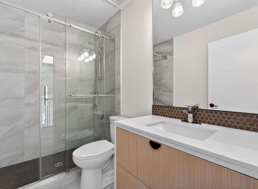 Step into a modern bathroom oasis! This stunning space features a sleek glass shower, elegant vanity, and stylish tile work.