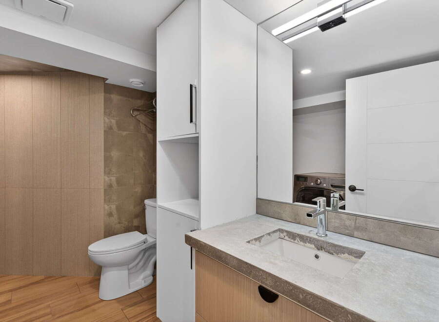 Step into a modern bathroom oasis! This space features sleek white cabinetry, a stylish sink, and a convenient laundry area.