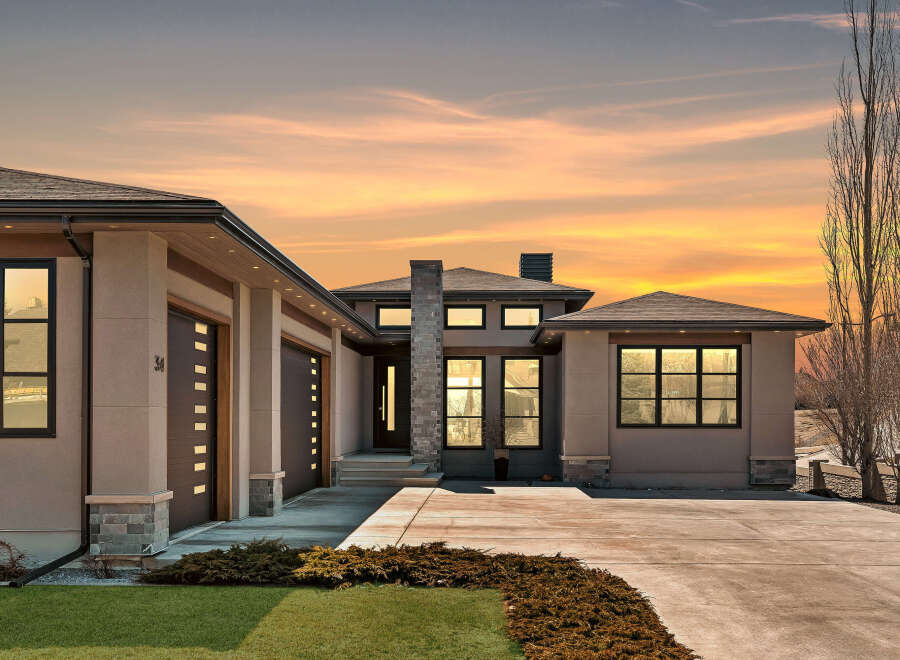 This stunning modern home boasts a sleek design with a spacious driveway and a beautifully landscaped front yard.