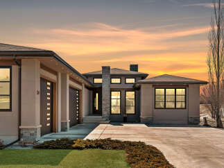 This stunning modern home boasts a sleek design with a spacious driveway and a beautifully landscaped front yard.
