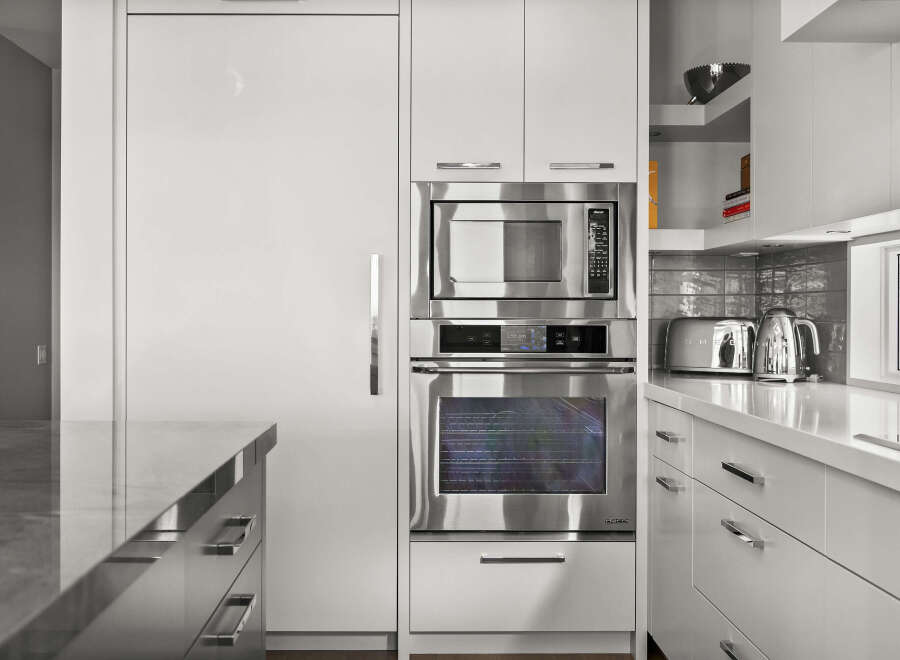 This modern kitchen boasts sleek, stainless steel appliances, including a microwave and oven, seamlessly integrated into the minimalist design.