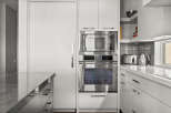 This modern kitchen boasts sleek, stainless steel appliances, including a microwave and oven, seamlessly integrated into the minimalist design.