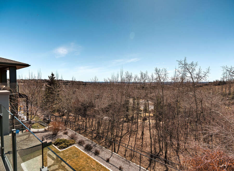 Enjoy breathtaking views from this stunning property! This home boasts a spacious balcony overlooking a serene landscape of trees and a clear blue sky.