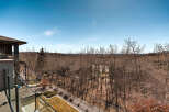 Enjoy breathtaking views from this stunning property! This home boasts a spacious balcony overlooking a serene landscape of trees and a clear blue sky.