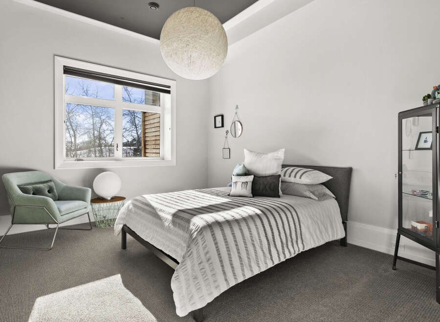 Step into this serene bedroom, featuring a comfortable bed and a stylish armchair.