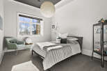 Step into this serene bedroom, featuring a comfortable bed and a stylish armchair.