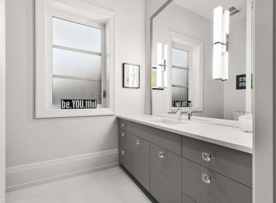 This modern bathroom boasts a sleek design with a gray vanity and crystal knobs.