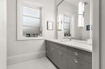 This modern bathroom boasts a sleek design with a gray vanity and crystal knobs.