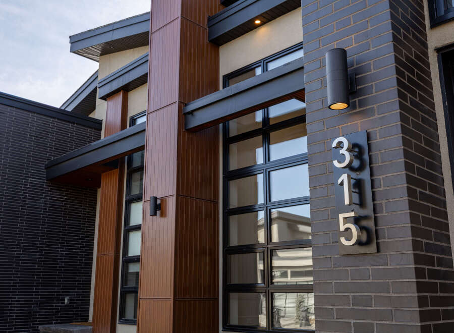 This stunning modern home showcases a sleek design with a combination of wood and brick exterior.