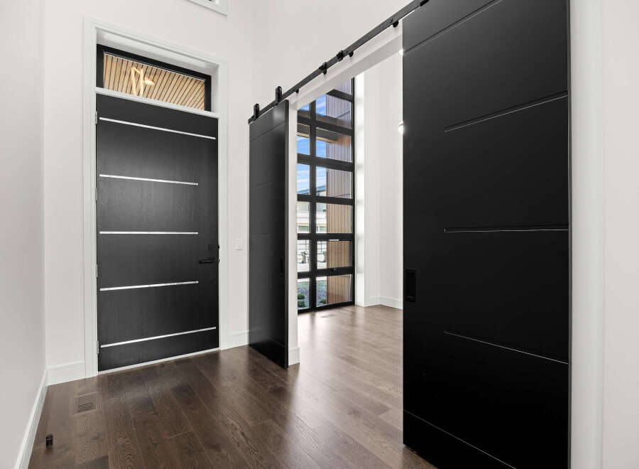 Step into modern elegance with this stunning property, featuring sleek black doors and a welcoming entryway.