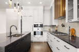 This stunning kitchen boasts modern design with sleek white cabinetry and a contrasting dark island.