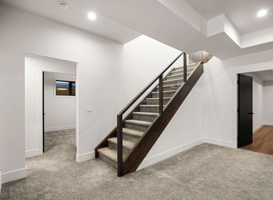 This stunning property features a modern staircase with dark wood accents and glass railings, creating an elegant focal point.