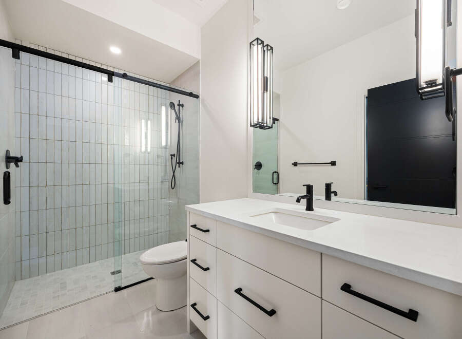 This modern bathroom features a sleek, minimalist design with a spacious walk-in shower and a stylish vanity.