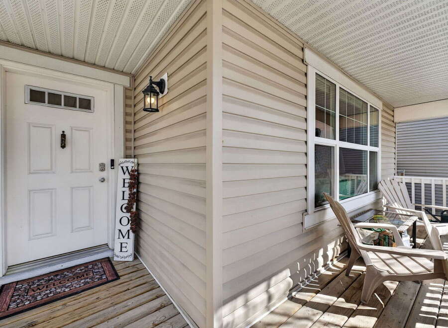 Welcome to your new home! This charming property features a welcoming front porch with a 'Welcome' sign and a cozy seating area.