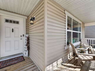 Welcome to your new home! This charming property features a welcoming front porch with a 'Welcome' sign and a cozy seating area.