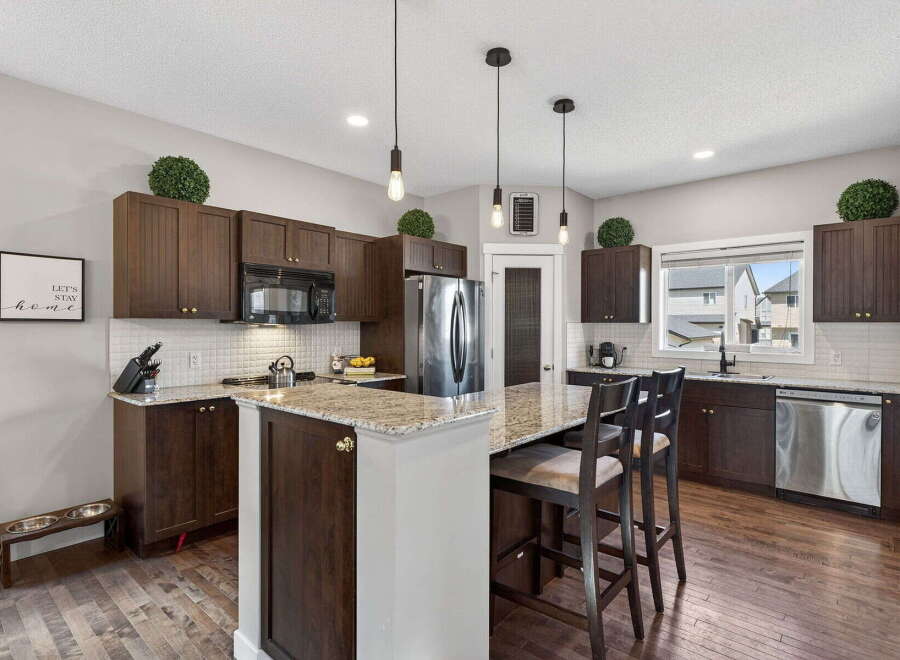 This stunning kitchen boasts dark wood cabinetry, a spacious island with seating, and elegant granite countertops.