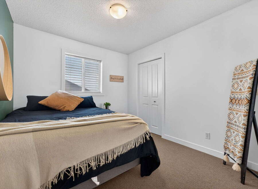 Step into this inviting bedroom, featuring a cozy bed adorned with plush pillows and a stylish throw.