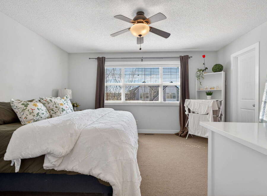 This inviting bedroom features a cozy bed with a plush white comforter and decorative pillows, creating a relaxing atmosphere.