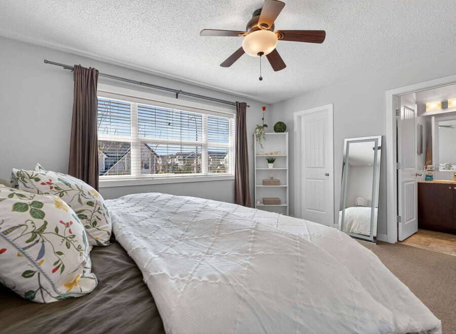 Step into this inviting bedroom, featuring a cozy bed adorned with decorative pillows and a stylish white quilt.