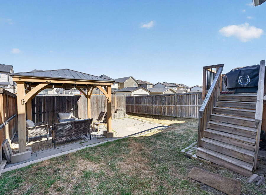 Enjoy outdoor living in this beautiful backyard! Featuring a gazebo, patio area, and a wooden staircase leading to the house, this space is perfect for entertaining or relaxing.
