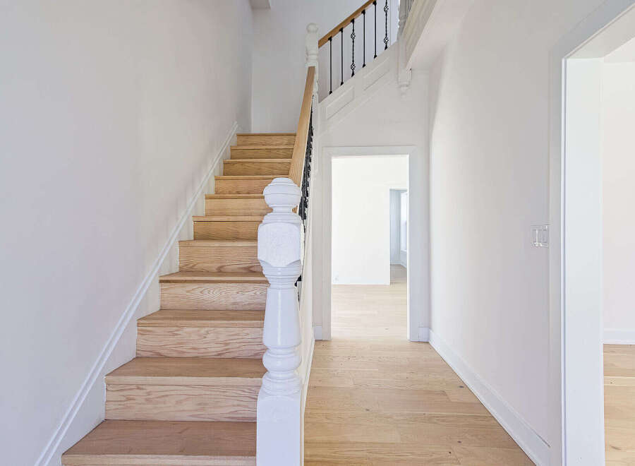 This stunning property features a beautifully crafted staircase with wooden steps and a white banister, creating a warm and inviting atmosphere.