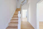 This stunning property features a beautifully crafted staircase with wooden steps and a white banister, creating a warm and inviting atmosphere.