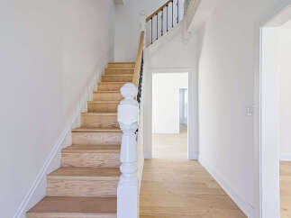 This stunning property features a beautifully crafted staircase with wooden steps and a white banister, creating a warm and inviting atmosphere.