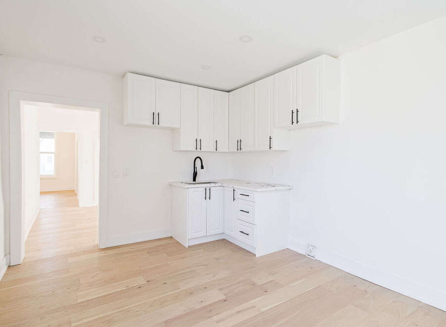 Discover this beautifully designed property featuring a modern kitchen with sleek white cabinetry and a stylish black faucet.