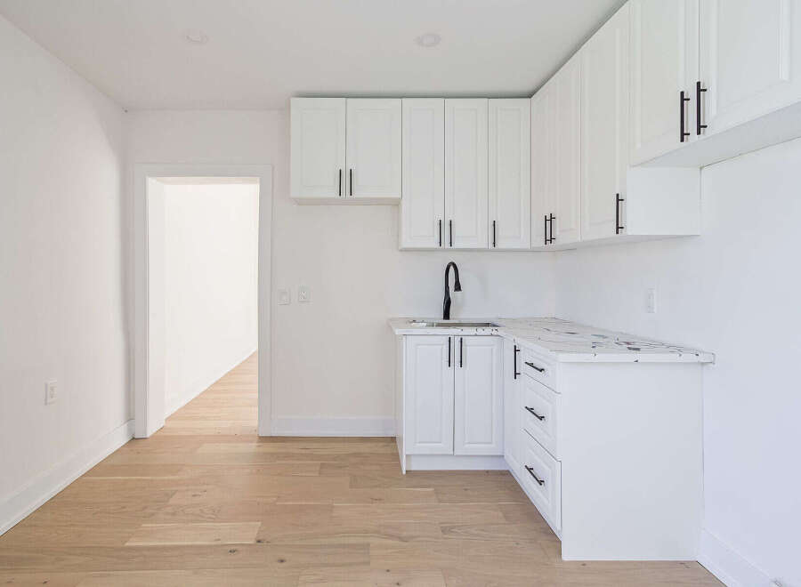 This modern kitchen features sleek white cabinetry and a stylish black faucet, creating a clean and contemporary aesthetic.