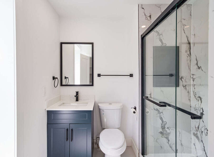 This modern bathroom boasts a sleek design with a navy blue vanity and a pristine white countertop.