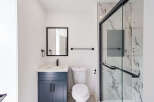 This modern bathroom boasts a sleek design with a navy blue vanity and a pristine white countertop.